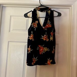 a navy floral blouse that is connected with a neck peace that Unbuttons